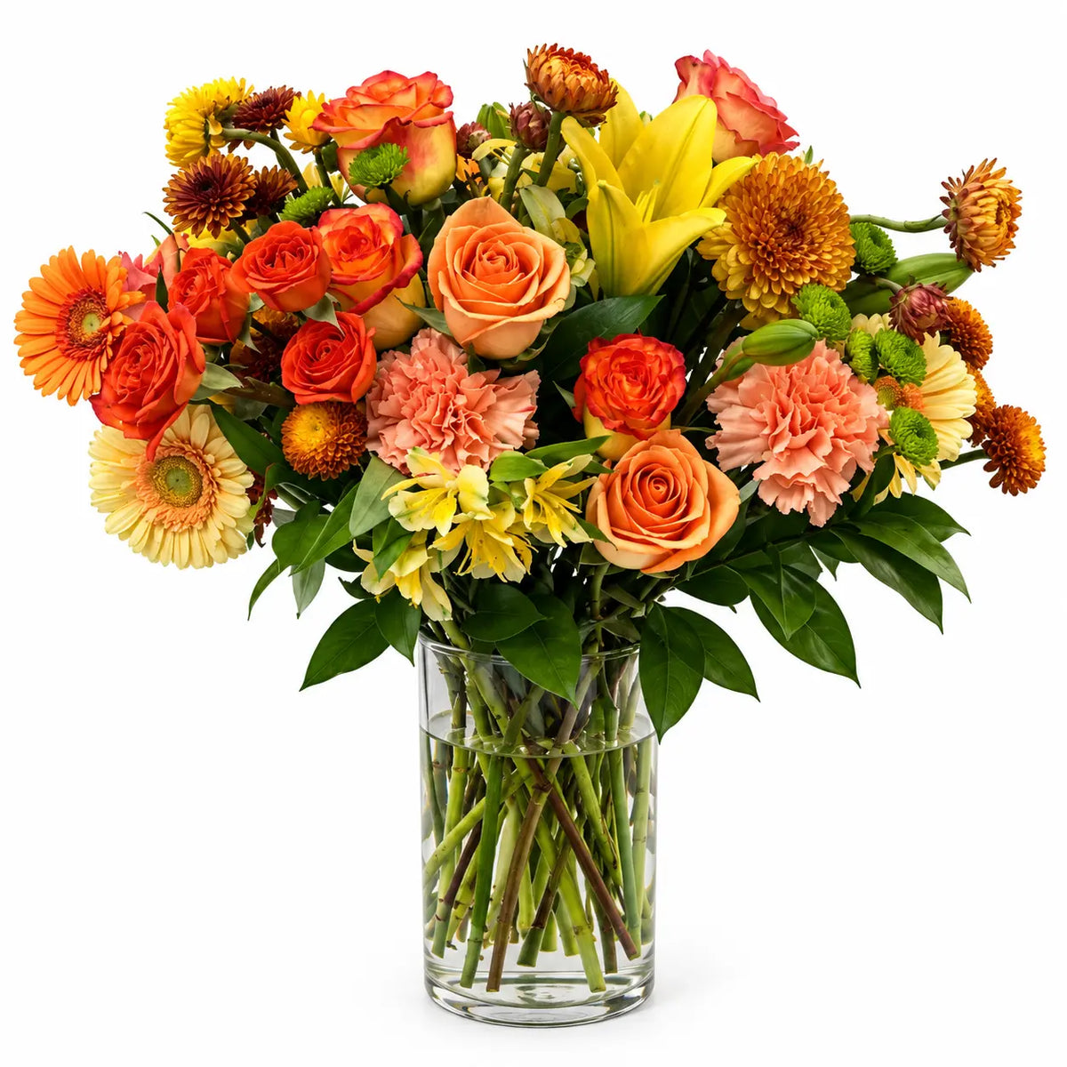 Orange and peach roses, yellow lilies, gerbera daisies, carnations, and chrysanthemums with greenery in a clear glass vase.